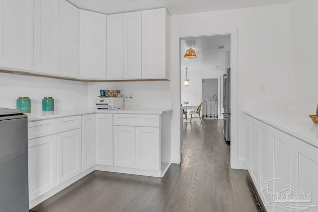 6050 Cheyenne Dr, Milton, FL 32570 - kitchen featuring light countertops, dark wood-style flooring, white cabinets, and freestanding refrigerator