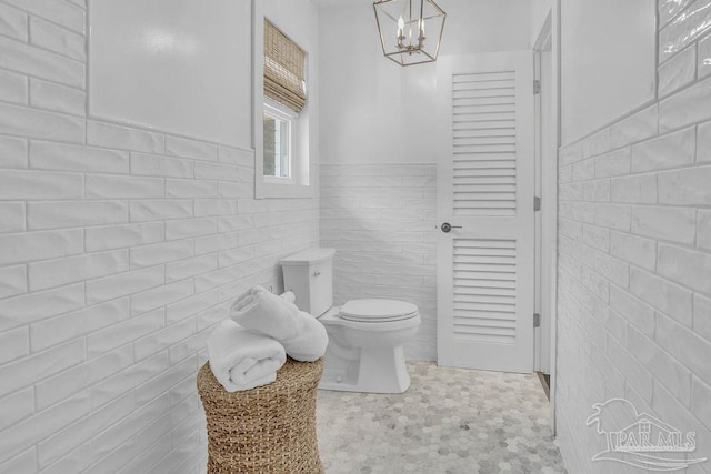 6050 Cheyenne Dr, Milton, FL 32570 - bathroom featuring toilet, tile walls, a chandelier, and a wainscoted wall