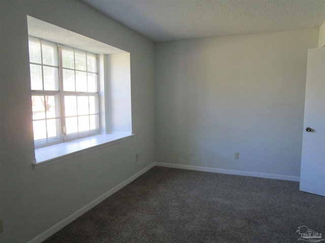 unfurnished room with a textured ceiling and dark colored carpet