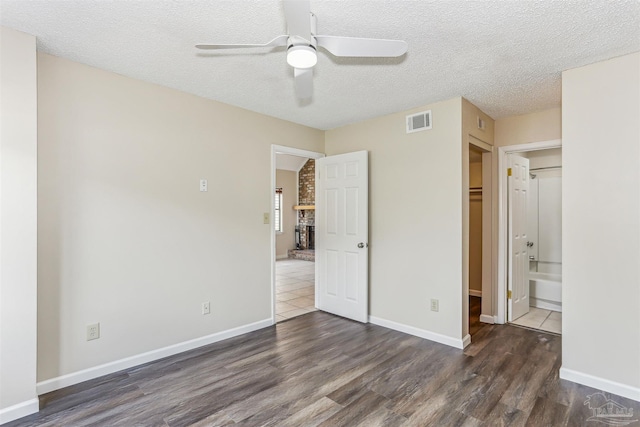 unfurnished bedroom with baseboards, a textured ceiling, visible vents, and wood finished floors