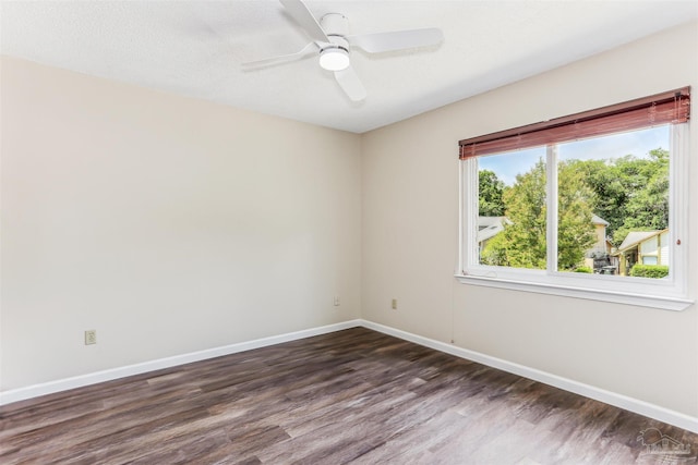 unfurnished room featuring baseboards, ceiling fan, and dark wood-type flooring