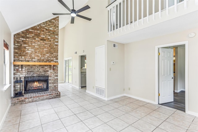 unfurnished living room featuring high vaulted ceiling, ceiling fan, a brick fireplace, and visible vents