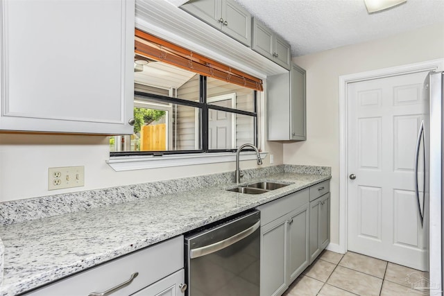 kitchen with stainless steel appliances, gray cabinets, light tile patterned floors, and a sink