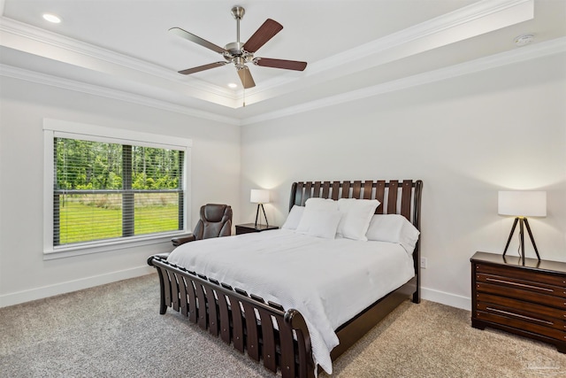 bedroom featuring ceiling fan, a raised ceiling, light colored carpet, and crown molding