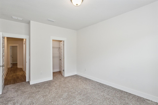 unfurnished bedroom featuring light colored carpet, a spacious closet, and a closet