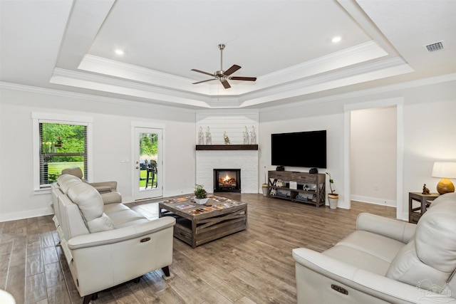 living room featuring a raised ceiling, ceiling fan, light hardwood / wood-style flooring, and ornamental molding