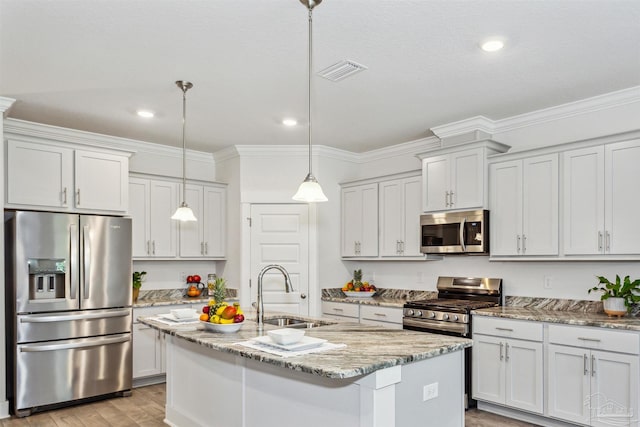 kitchen featuring light stone counters, stainless steel appliances, sink, hanging light fixtures, and an island with sink