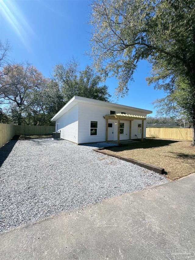 view of front of house featuring driveway, fence, and central AC unit