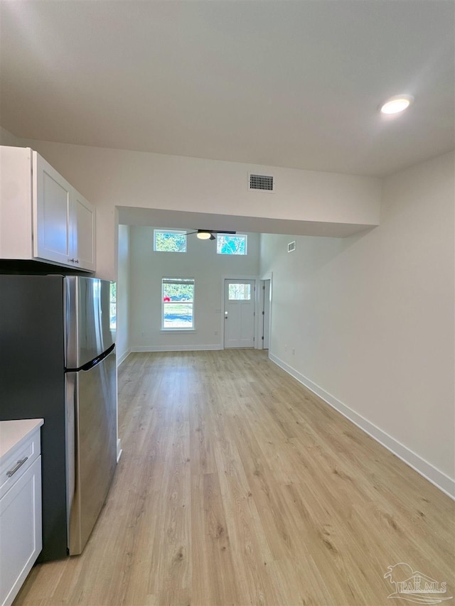 kitchen with white cabinetry, visible vents, open floor plan, and freestanding refrigerator