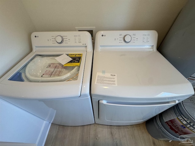 clothes washing area with laundry area, washer and clothes dryer, and wood finished floors