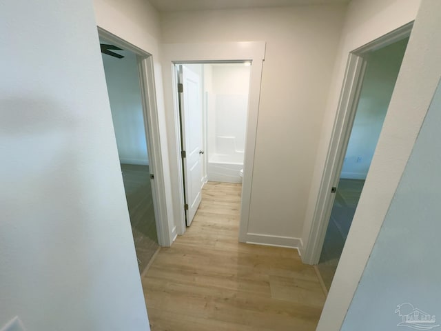 hall featuring light wood-type flooring and baseboards