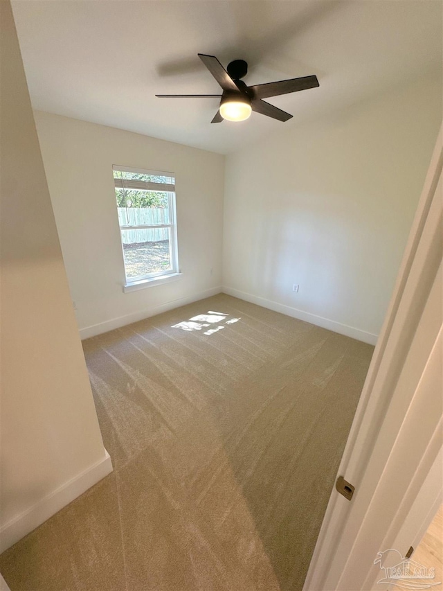 spare room with light carpet, baseboards, and a ceiling fan