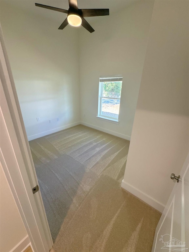 carpeted spare room with a ceiling fan and baseboards