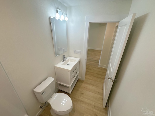 bathroom featuring baseboards, vanity, toilet, and wood finished floors