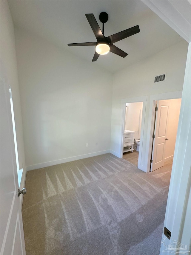 unfurnished bedroom with visible vents, ensuite bathroom, carpet flooring, vaulted ceiling, and baseboards