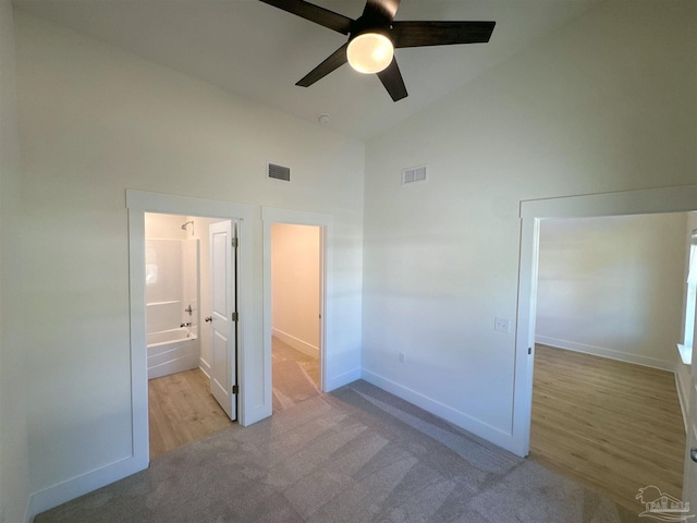 unfurnished bedroom featuring high vaulted ceiling, carpet flooring, visible vents, and baseboards