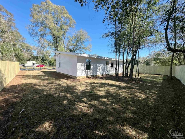 rear view of property with a fenced backyard and a lawn