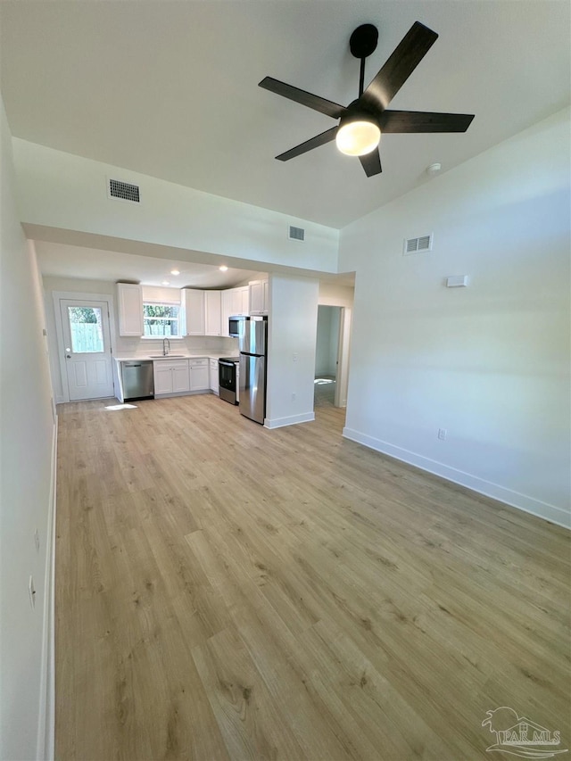 unfurnished living room featuring light wood-type flooring, visible vents, and a sink