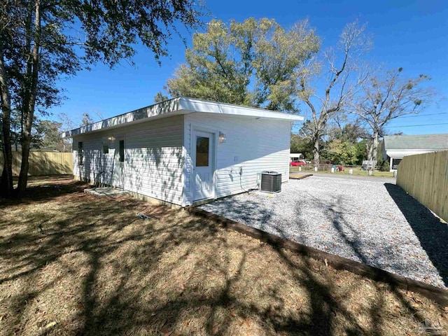 exterior space with an outbuilding, fence, driveway, and central AC unit