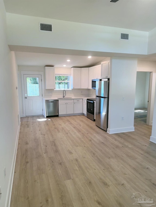 kitchen with light wood finished floors, visible vents, stainless steel appliances, and a sink