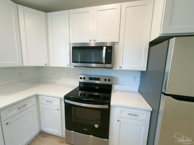 kitchen featuring stainless steel appliances, light countertops, and white cabinets