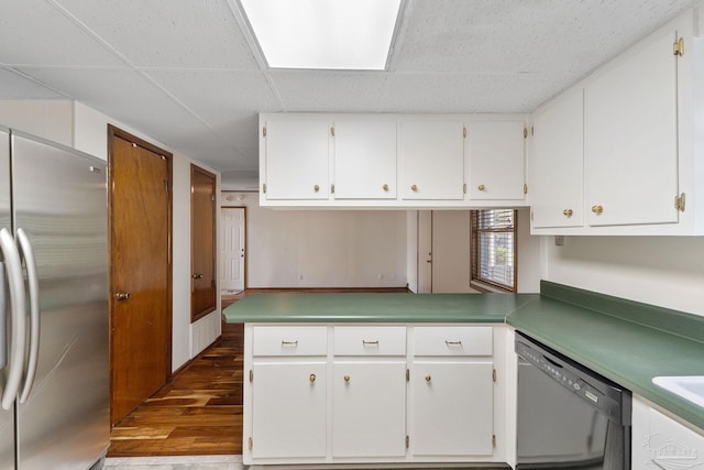 kitchen with white cabinets, appliances with stainless steel finishes, kitchen peninsula, and hardwood / wood-style floors