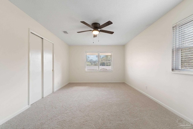 carpeted spare room with a wealth of natural light, ceiling fan, and a textured ceiling