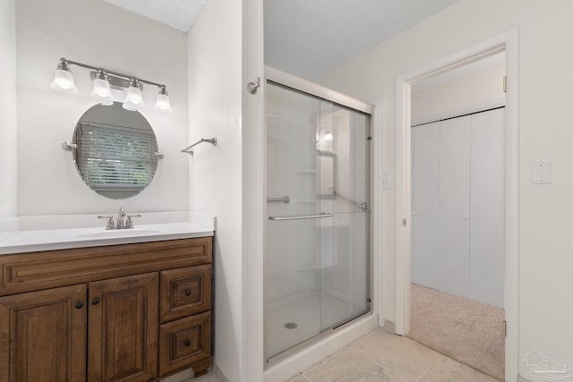 bathroom with tile patterned flooring, vanity, a textured ceiling, and walk in shower