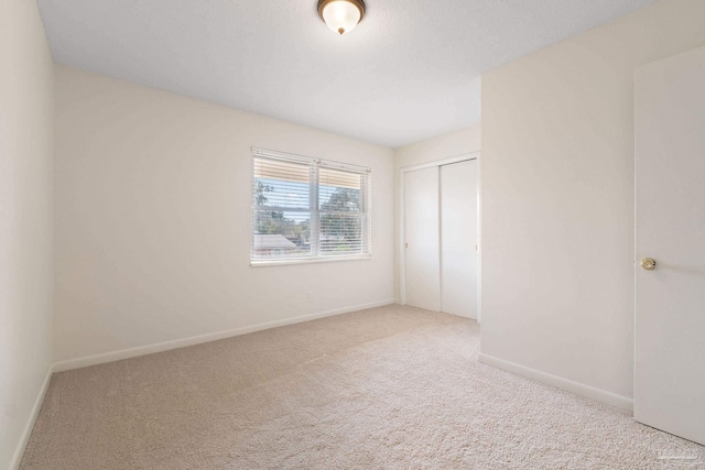 unfurnished bedroom with light colored carpet and a closet