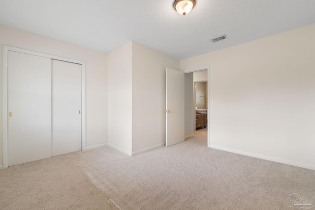 unfurnished bedroom featuring light carpet and a closet