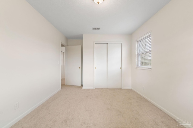 unfurnished bedroom featuring light colored carpet and a closet