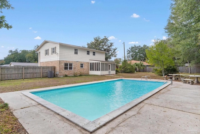 view of swimming pool featuring a patio area, a sunroom, and central AC unit