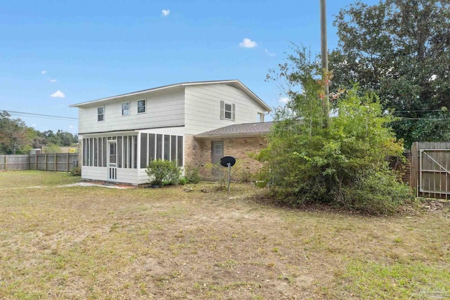 rear view of house with a sunroom and a yard