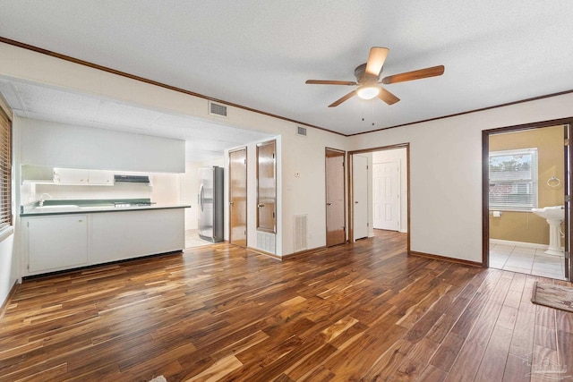 unfurnished living room with ornamental molding, a textured ceiling, ceiling fan, dark wood-type flooring, and sink