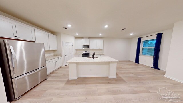 kitchen featuring white cabinetry, appliances with stainless steel finishes, sink, and an island with sink