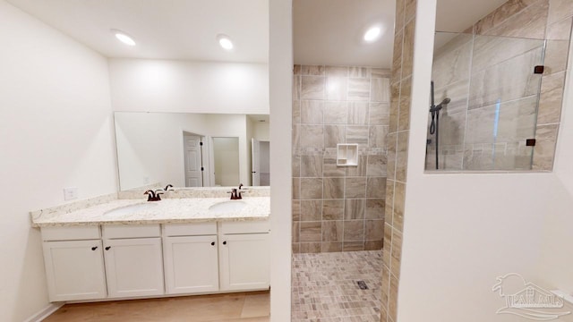 bathroom with tiled shower, tile patterned flooring, and vanity