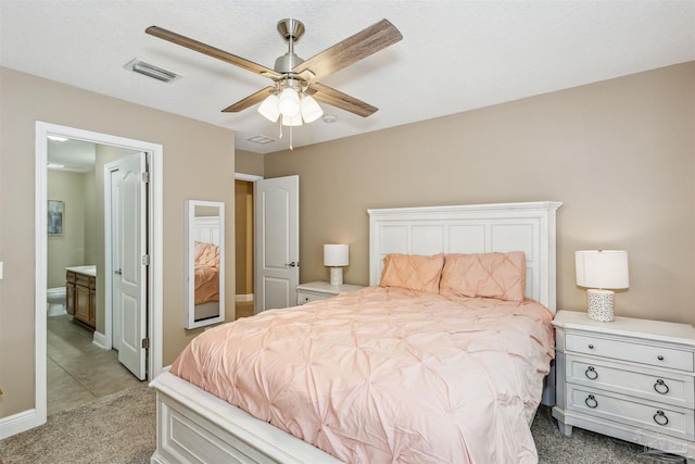 bedroom with ceiling fan, ensuite bath, and light carpet