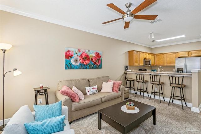 carpeted living room featuring ornamental molding, sink, and ceiling fan