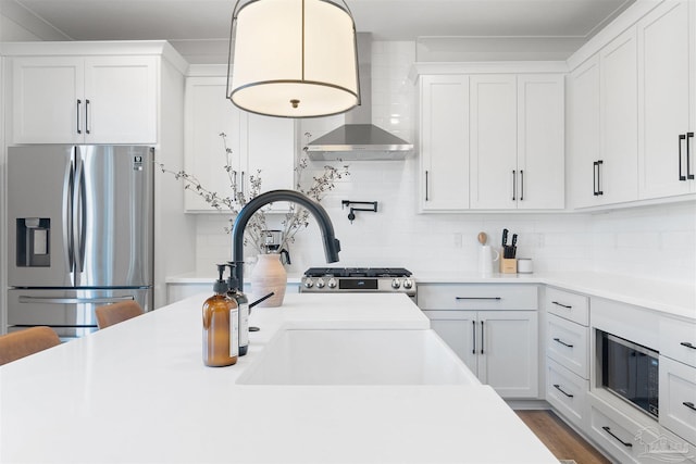 13844 Red Drum Ct, Perdido Key, FL 32507 - kitchen featuring appliances with stainless steel finishes, wall chimney exhaust hood, decorative backsplash, light countertops, and white cabinetry