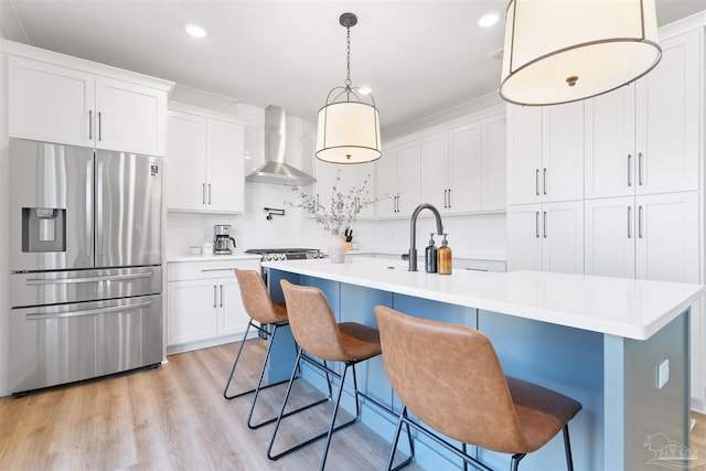13844 Red Drum Ct, Perdido Key, FL 32507 - kitchen featuring stainless steel appliances, wall chimney range hood, light countertops, white cabinetry, and decorative backsplash