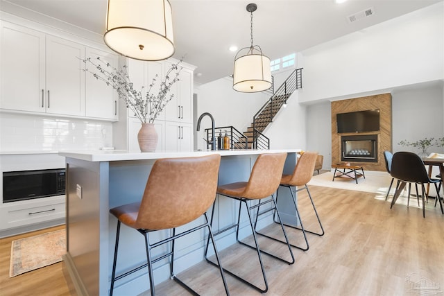 13844 Red Drum Ct, Perdido Key, FL 32507 - kitchen with black microwave, light wood-style flooring, a large fireplace, a kitchen breakfast bar, and tasteful backsplash