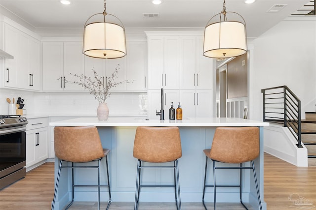 13844 Red Drum Ct, Perdido Key, FL 32507 - kitchen with stainless steel range, light wood finished floors, white cabinets, decorative backsplash, and recessed lighting