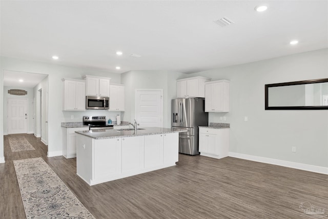 kitchen featuring a sink, stainless steel appliances, dark wood-style floors, baseboards, and a center island with sink