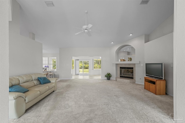 carpeted living area with visible vents, a fireplace, a high ceiling, and a ceiling fan