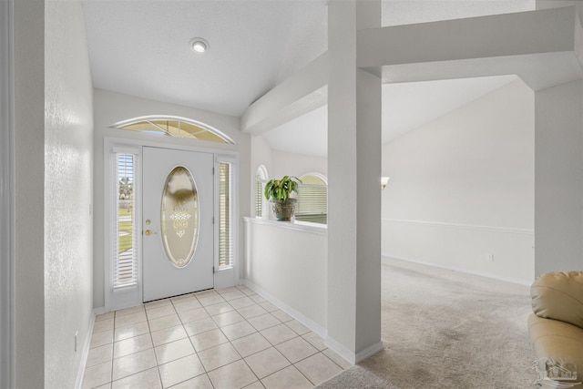 foyer with baseboards, light colored carpet, light tile patterned flooring, and a textured wall