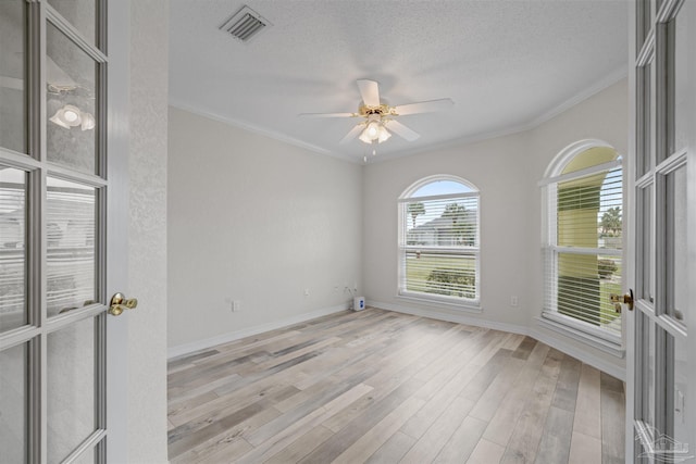 unfurnished room with visible vents, ornamental molding, a ceiling fan, a textured ceiling, and light wood-style floors