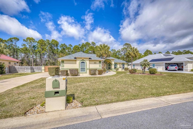 view of front of house with a front lawn, fence, driveway, and stucco siding