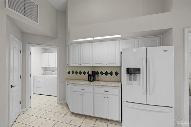 kitchen with visible vents, decorative backsplash, white refrigerator with ice dispenser, white cabinets, and independent washer and dryer