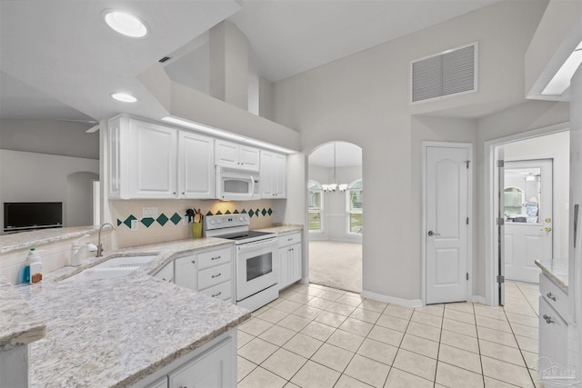 kitchen with white appliances, visible vents, arched walkways, a sink, and white cabinets