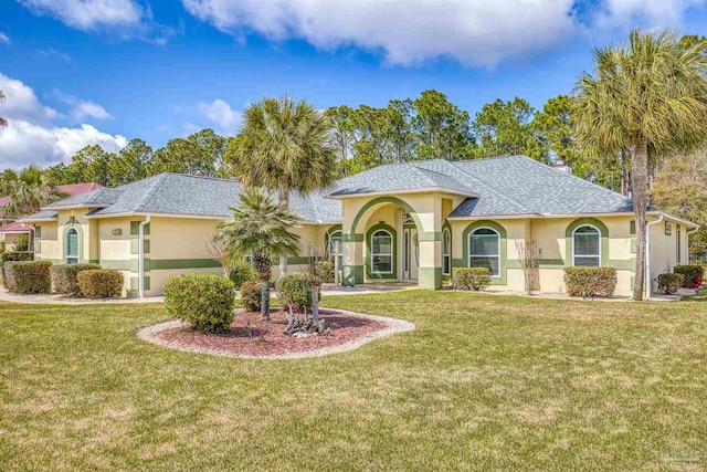 mediterranean / spanish home featuring stucco siding, roof with shingles, and a front yard